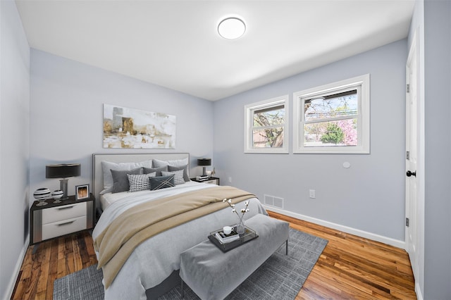 bedroom with baseboards, wood finished floors, and visible vents