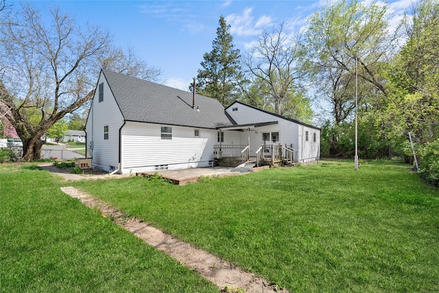 rear view of property featuring a patio, a shingled roof, a lawn, and a deck