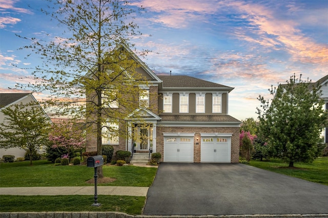 view of front of property with a shingled roof, brick siding, a garage, a front yard, and driveway