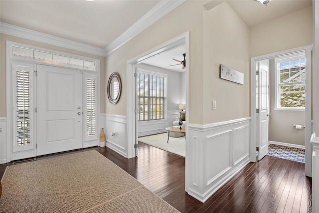 entrance foyer with crown molding, a ceiling fan, wainscoting, and dark wood-style flooring