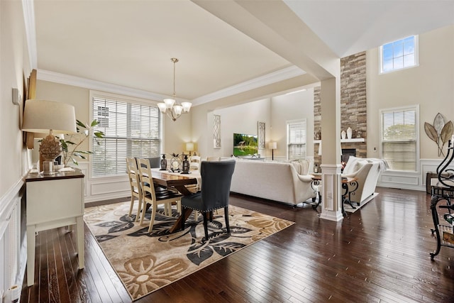 dining room featuring wainscoting, a decorative wall, a fireplace, dark wood-style floors, and a chandelier