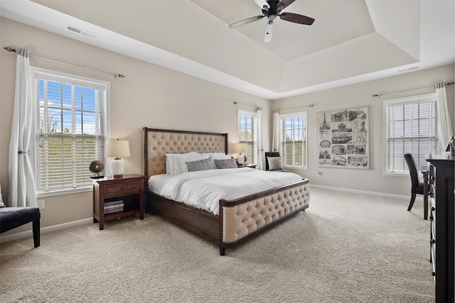 bedroom featuring baseboards, visible vents, light carpet, and a raised ceiling
