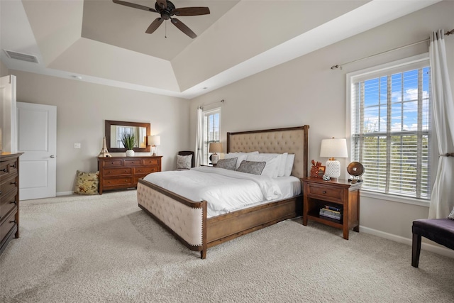 bedroom with visible vents, baseboards, light colored carpet, and a raised ceiling