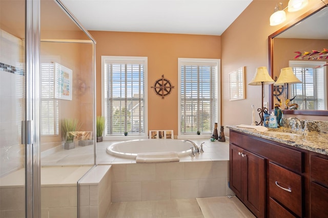 full bath featuring a garden tub, a shower with shower door, and vanity