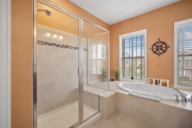 bathroom with tile patterned floors, a healthy amount of sunlight, a garden tub, and a stall shower