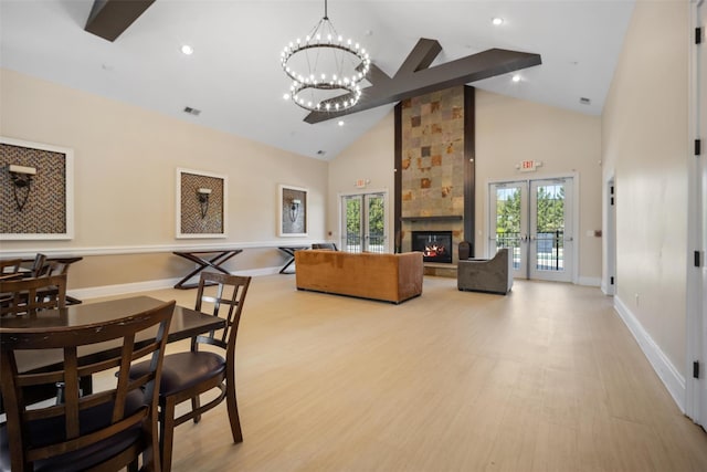 living area with an inviting chandelier, light wood-style floors, a healthy amount of sunlight, and high vaulted ceiling