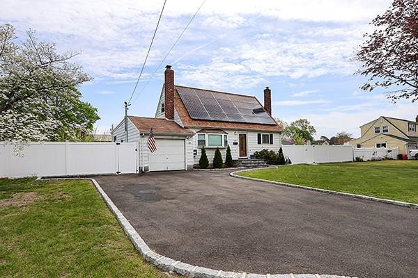 view of front of home with solar panels, a chimney, a front yard, fence, and an attached garage