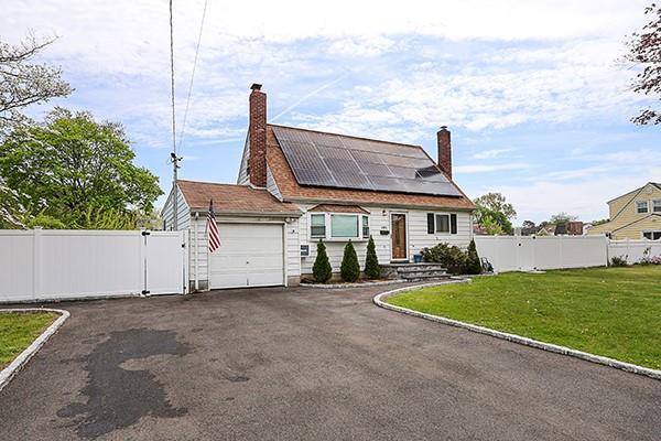 view of front facade featuring roof mounted solar panels, fence, an attached garage, and a front lawn