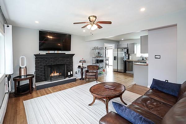living area featuring a brick fireplace, wood finished floors, ceiling fan, recessed lighting, and a wealth of natural light