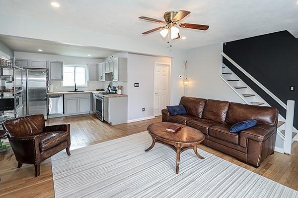 living room featuring baseboards, stairway, recessed lighting, a ceiling fan, and light wood finished floors
