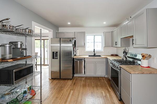 kitchen with light countertops, gray cabinets, a sink, light wood-style flooring, and stainless steel appliances