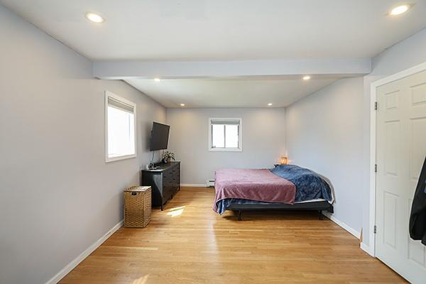 bedroom with beam ceiling, baseboards, a baseboard radiator, light wood-style floors, and recessed lighting