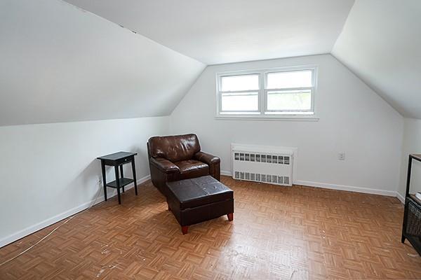 sitting room featuring baseboards, vaulted ceiling, and radiator
