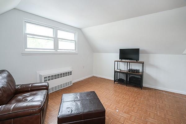 living area with baseboards, radiator, and vaulted ceiling