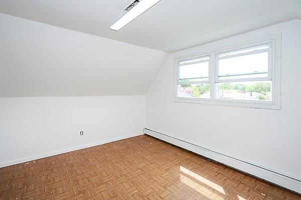 bonus room featuring baseboards, visible vents, lofted ceiling, and a baseboard radiator