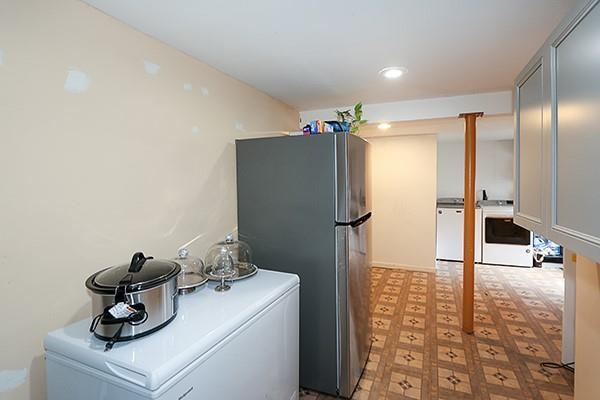 kitchen featuring freestanding refrigerator, light floors, and washer / clothes dryer
