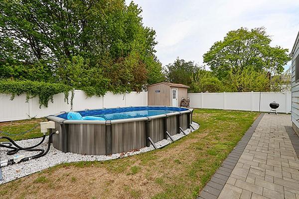 view of swimming pool with a lawn, a fenced backyard, a storage shed, and a fenced in pool