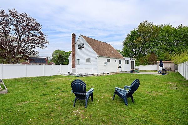 back of property featuring a fenced backyard, a chimney, and a lawn