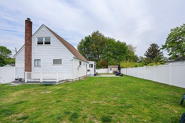 back of house featuring a fenced backyard, a chimney, and a lawn