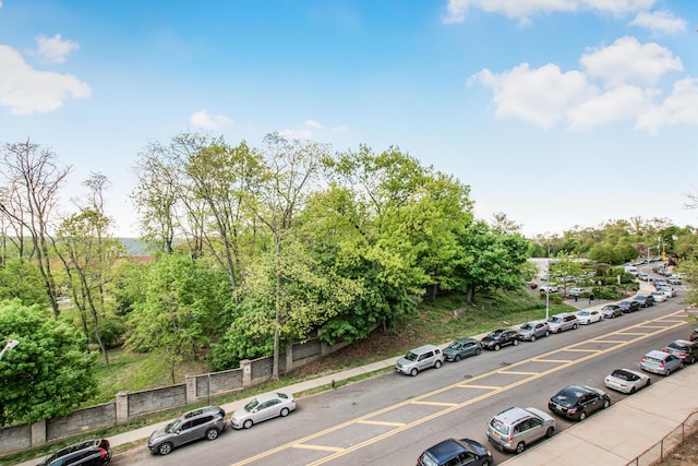 view of parking with view of wooded area