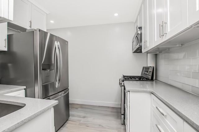 kitchen featuring stainless steel appliances, white cabinets, backsplash, recessed lighting, and light stone countertops