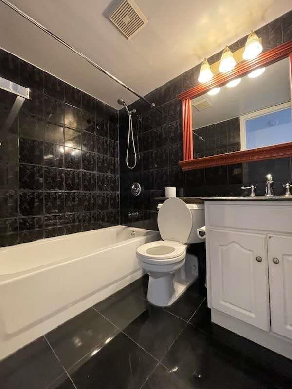 full bathroom with shower / tub combination, toilet, tile patterned floors, tile walls, and visible vents