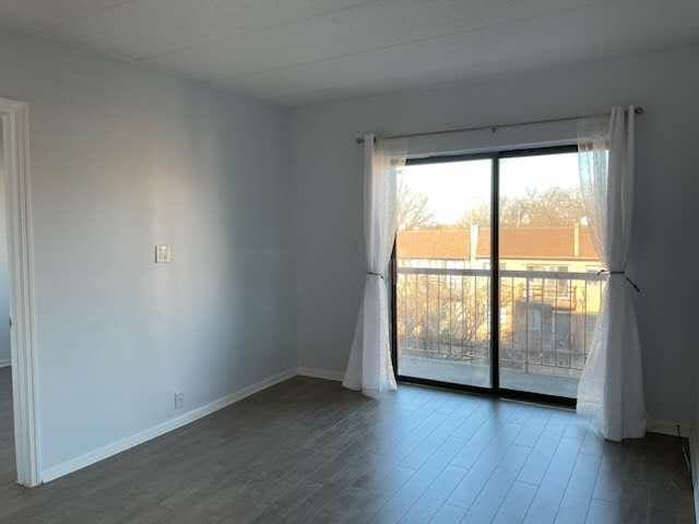 spare room featuring baseboards and wood finished floors
