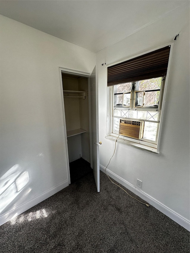 unfurnished bedroom with baseboards, cooling unit, a closet, and dark colored carpet