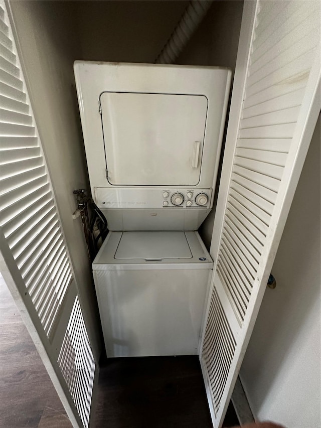 clothes washing area featuring laundry area, stacked washer and clothes dryer, and wood finished floors