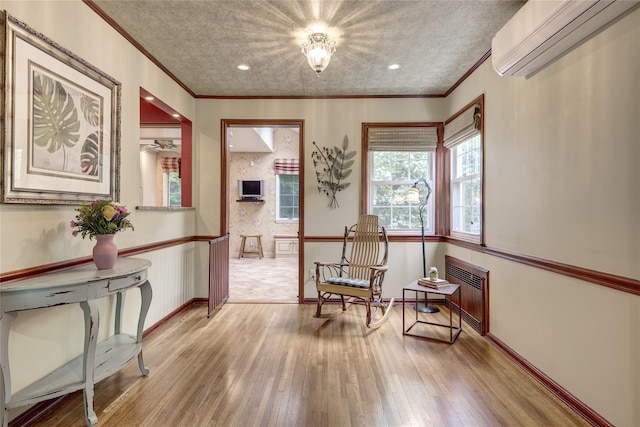 living area featuring a wall unit AC, radiator heating unit, light wood-style flooring, ornamental molding, and baseboards