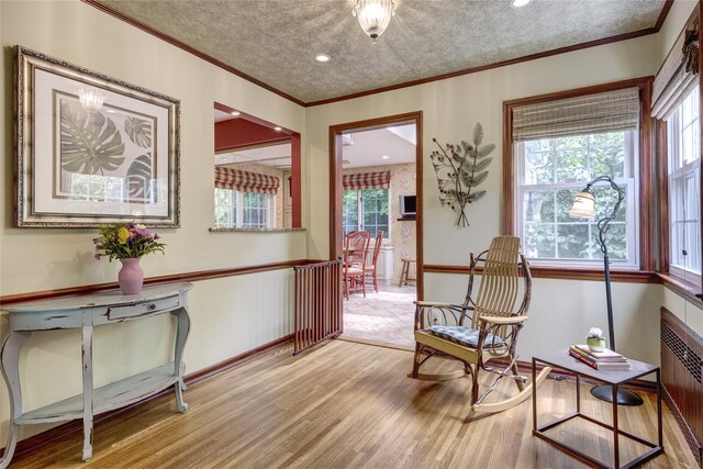 living area with radiator heating unit, wood finished floors, ornamental molding, and baseboards