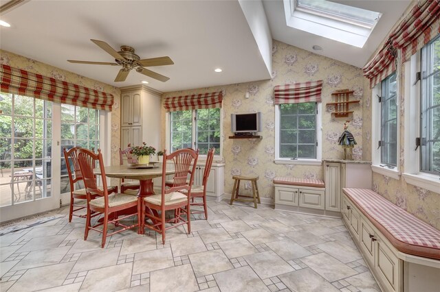 dining area featuring healthy amount of natural light, wallpapered walls, a ceiling fan, a skylight, and lofted ceiling