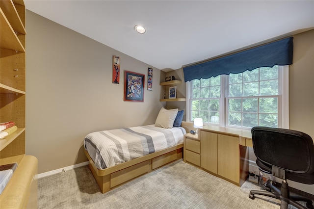 bedroom featuring an office area, light colored carpet, and baseboards