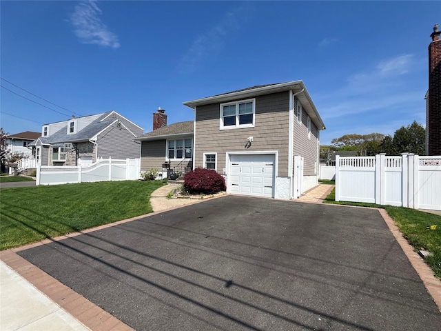 split level home featuring a garage, fence, a front lawn, and aphalt driveway