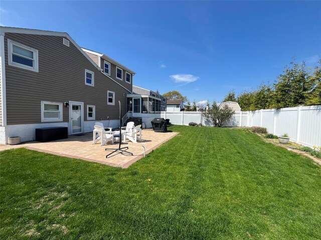 view of yard with a sunroom, a fenced backyard, and a patio area