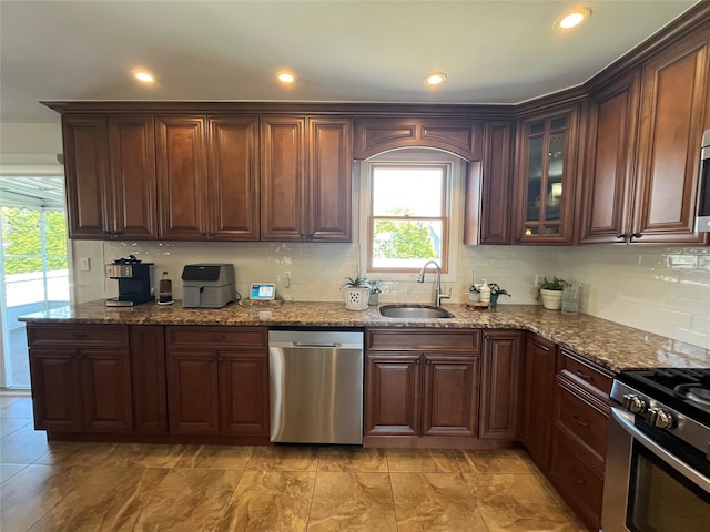 kitchen with decorative backsplash, a sink, dark stone countertops, stainless steel appliances, and recessed lighting