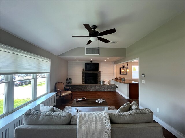 living area with a stone fireplace, a ceiling fan, wood finished floors, lofted ceiling, and visible vents