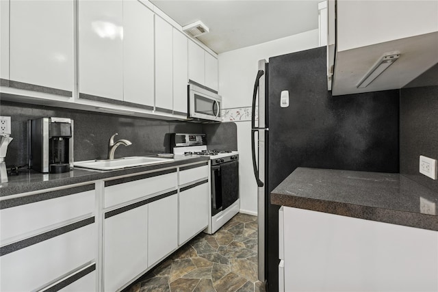 153-25 88th St Unit 3D, Howard Beach, NY 11414 - kitchen with appliances with stainless steel finishes, dark stone finish floors, dark countertops, white cabinetry, and backsplash