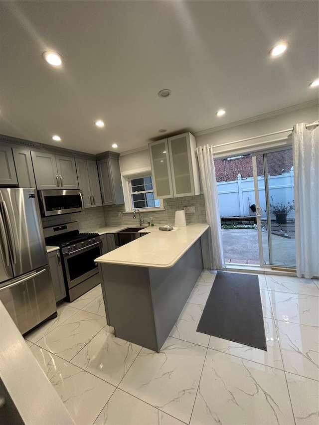 kitchen with stainless steel appliances, gray cabinetry, a peninsula, glass insert cabinets, and tasteful backsplash
