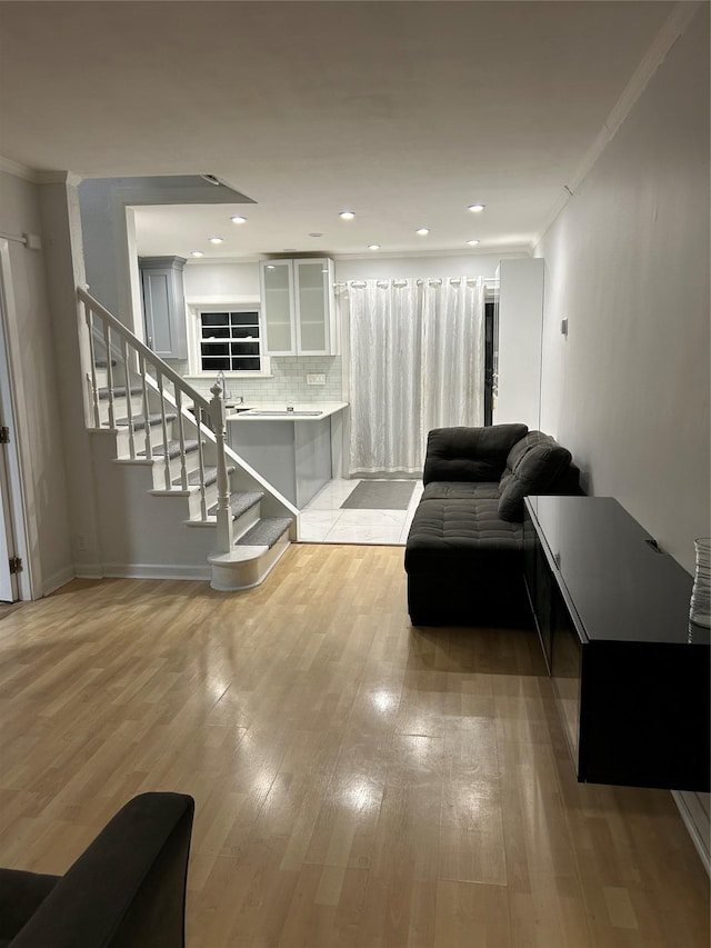 living area featuring crown molding, stairway, light wood-style flooring, baseboards, and recessed lighting
