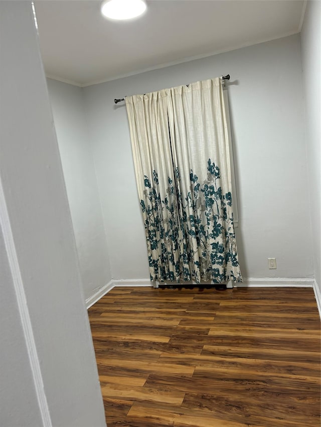 spare room with dark wood finished floors, baseboards, and crown molding