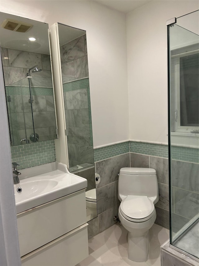 full bathroom featuring toilet, a stall shower, vanity, tile walls, and a wainscoted wall