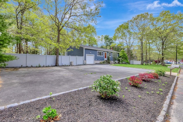 view of front of property with aphalt driveway, fence, an attached garage, and a chimney