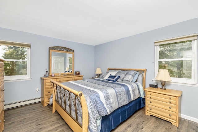 bedroom with multiple windows, wood finished floors, and baseboard heating