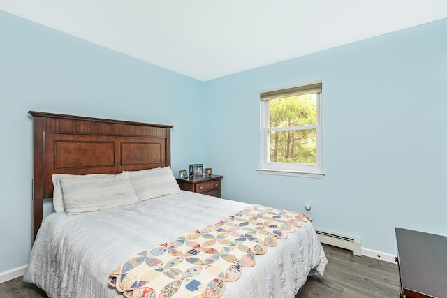 bedroom with a baseboard heating unit, baseboards, and dark wood-type flooring