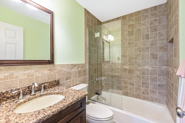 bathroom featuring tile walls, toilet,  shower combination, and vanity