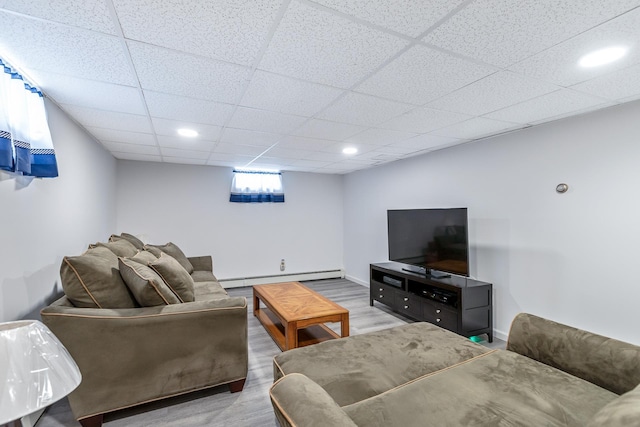 living room featuring a drop ceiling, baseboard heating, recessed lighting, baseboards, and wood finished floors
