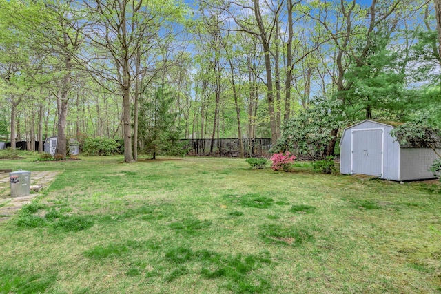 view of yard featuring an outdoor structure, fence, and a storage unit