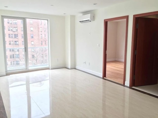 tiled spare room featuring baseboards and an AC wall unit