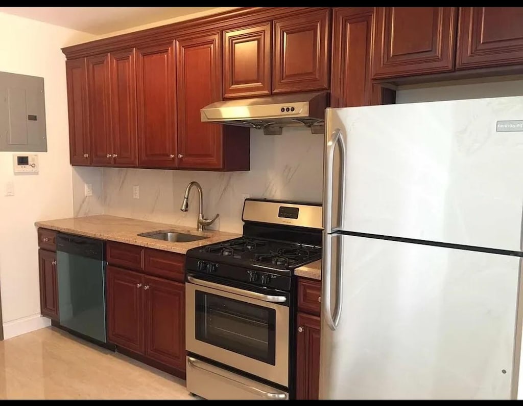 kitchen with gas range, a sink, freestanding refrigerator, dishwashing machine, and under cabinet range hood